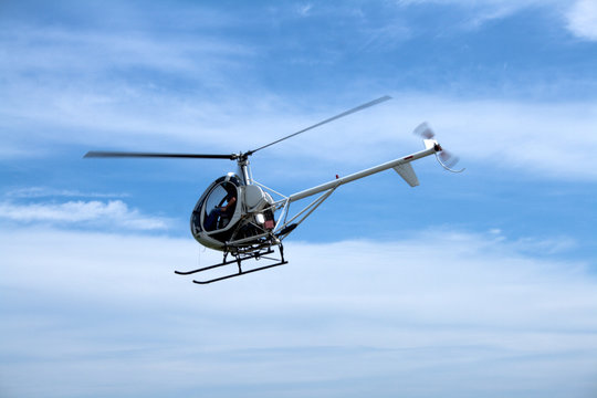 Small passenger helicopter hovering on blue sky