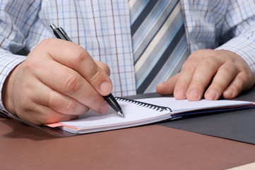 Fototapeta premium Close-up of a businessman's hand with a pen writing something.
