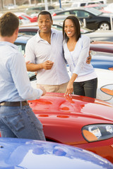 Young couple discussing new car with salesman