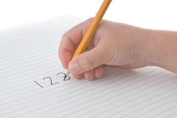 Child's hand holding pencil, writing numbers on paper