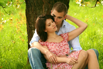 young and happy couple is cuddle on a meadow