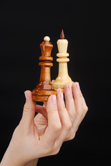 Two hands with chesspieces king and queen