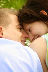 young and happy couple is smiling on a meadow