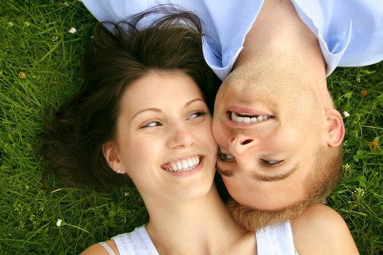 young and happy couple is smiling on a meadow