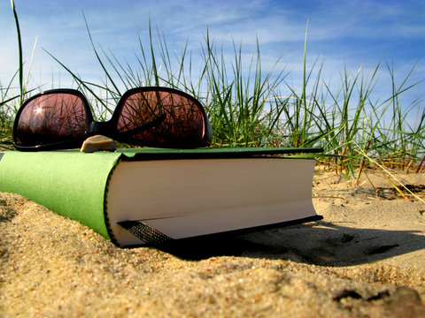 Urlaub am Strand mit Buch und Sonnenbrille