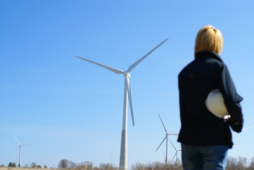 Woman engineer with white safety hat and wind turbines
