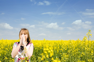 Naklejka na ściany i meble Young woman blowing her nose on the rape field