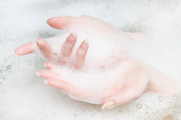 Fototapeta premium Woman hands in a bath with foam