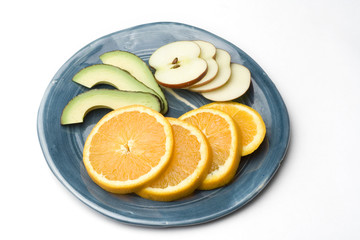 a blue plate with slices on orange apple and avocado
