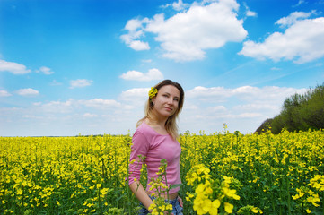 Fototapeta premium Beautiful girl among blooming rape oilseed field
