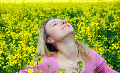 Beautiful girl among blooming rape oilseed field