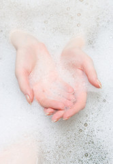 Woman hands in a bath with foam