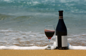Bottle and glass of wine on the beach