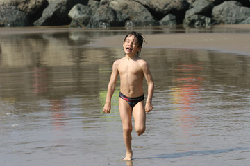 petit garçon souriant entrain de courir sur la plage