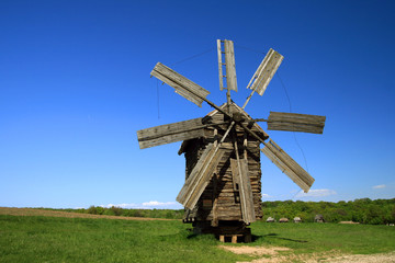 windmill with fresh green grass and clear blue sky in summer