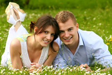 young and happy couple is smiling on a meadow