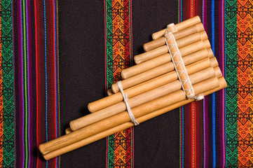siku, andean wind musical instrument, on traditional tapestry.
