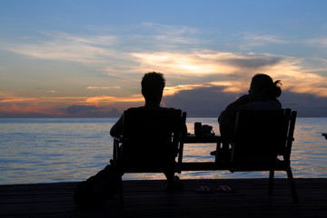Fototapeta na wymiar Couple in silhouette sharing sunset over ocean