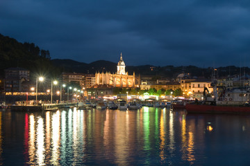 Fototapeta na wymiar Gothic basilica and harbour in Lekeitio at dusk