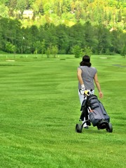 Golfer on golfcourse with golf bag