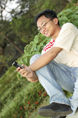 Asian Man Leaning Back Holding Mobile Phone