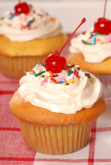 Golden cupcakes with buttercream, sprinkles and cherry