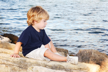 Young boy sitting by the edge of a lake