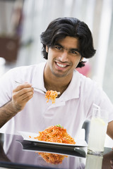 Man eating plate of pasta at cafe