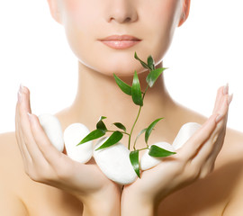 Beautiful young woman holding plant growing up through stones