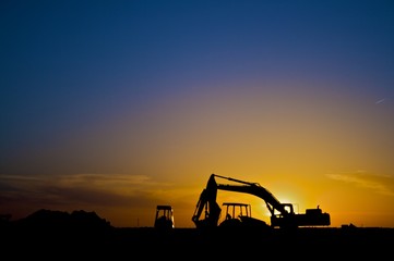 Construction equipment in silhouette, horizontal