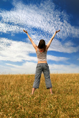 girl with his arms wide open on blue sky