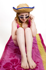young girl on towel looking over her sunglasses