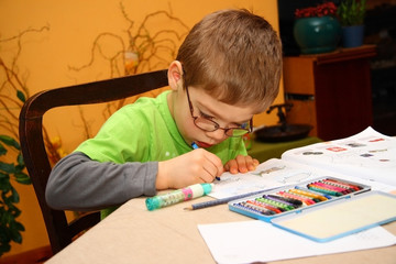 Young boy in glasses painting