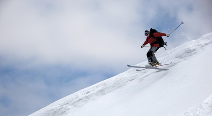 Skier jumping from the edge of snow ridge