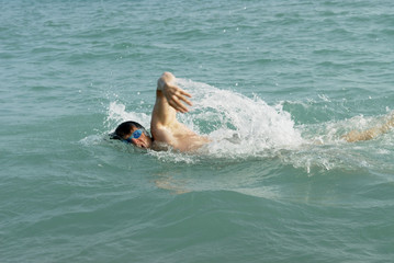 A man swimming front crawl in the sea.