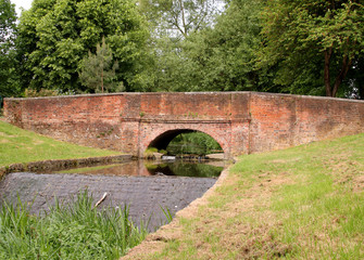 Fototapeta na wymiar Red Brick Bridge over a Stream