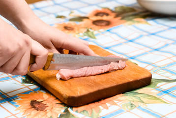 hands cutting raw meat