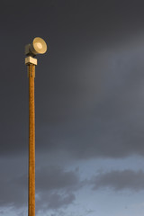 warning siren on a tall post against stormy sky