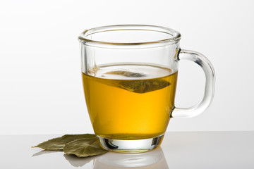 A cup of tea with tea bag and green leaves