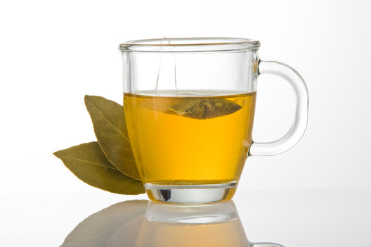 A cup of tea with tea bag and green leaves