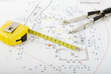 Bauplan mit Zirkel und Rollmeter