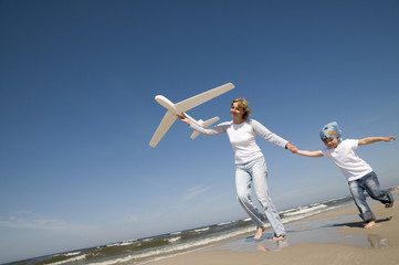 Family playing with plane model on the beach