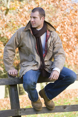 Obraz premium Young man sitting on fence