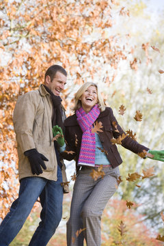 Young couple having throwing leaves in the air