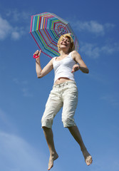 yong charming girl jumping with umbrella against blue sky