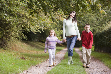 Fototapeta premium Mother and children walking along woodland path