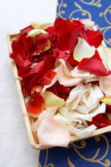 Petals of roses in a basket on a cloth of white and dark blue co