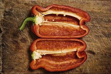 Red pepper cut in two pieces on wooden table.