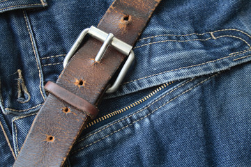 Close-up of old leather belt on background with old jeans