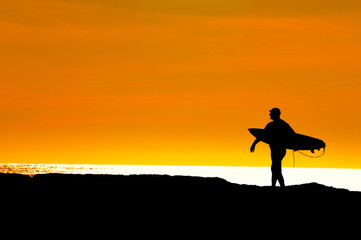 Surfer heading to sea for a sunset ride
